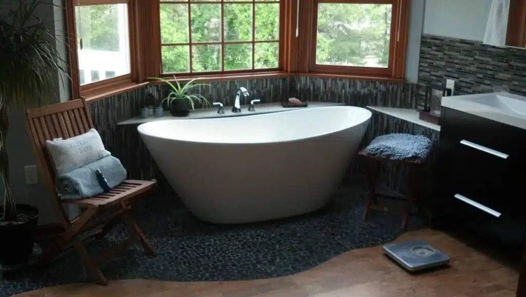 Sloped oval ivory bathtub in exotic, modern bathroom with plants, black carpet, and wood framed windows.