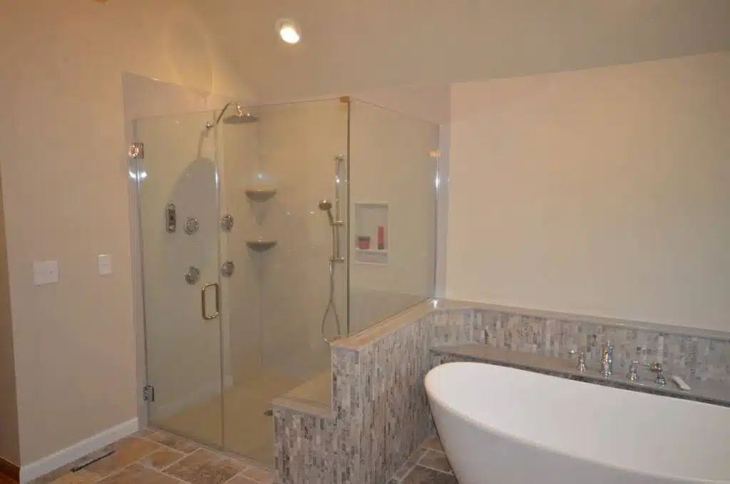 Sloped oval bathtub and fully glass shower combination.
