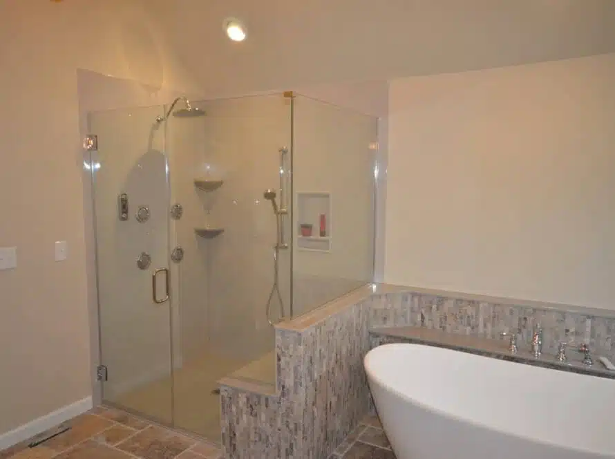 Sloped oval bathtub and fully glass shower combination.