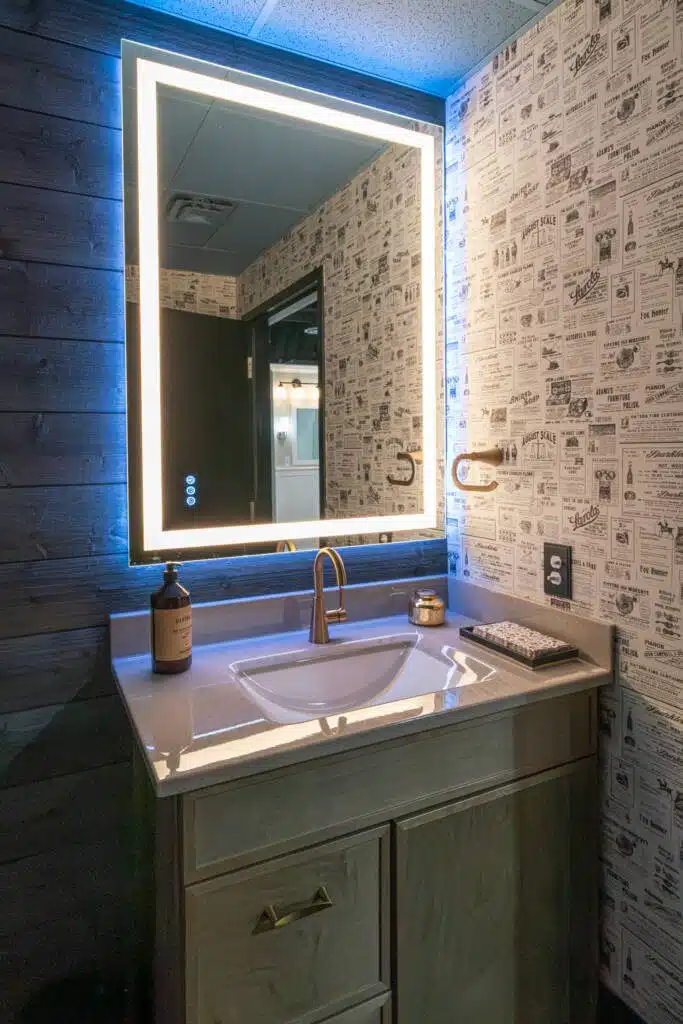 Bathroom design with retro newspaper wallpaper and touchscreen control mirror with blue neon glow and a built-in light.