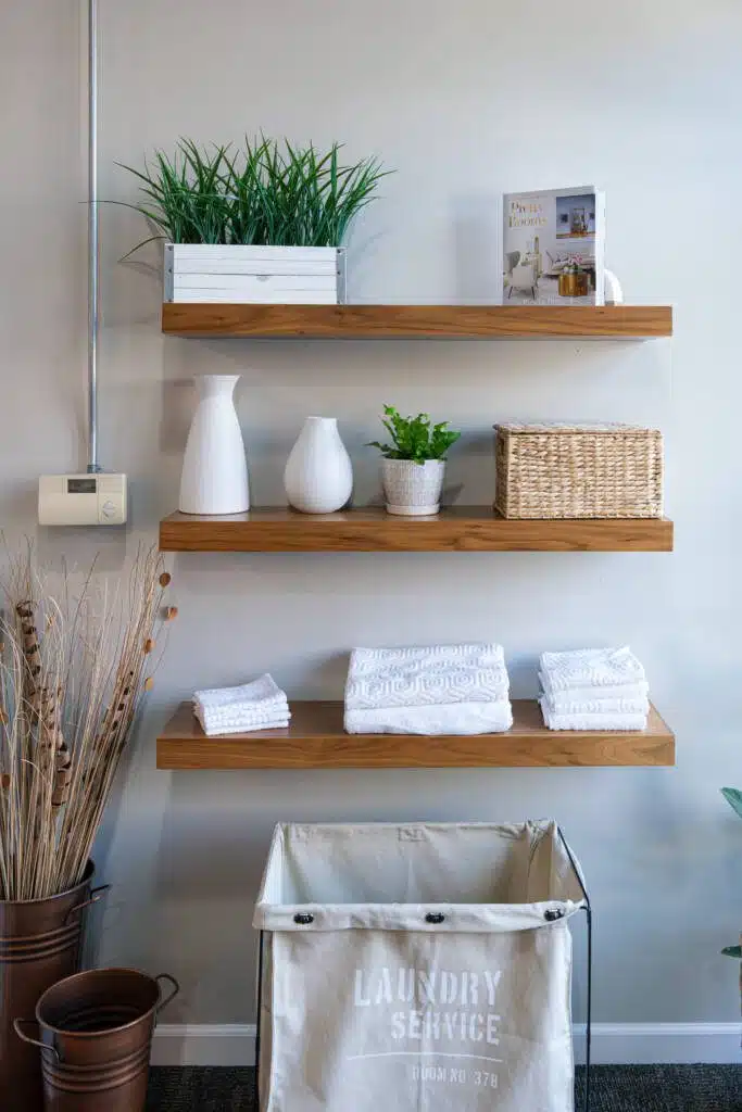 Clean and fresh wooden bathroom organization shelves with plants and products on it.